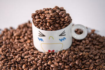 white cup with a pattern and coffee beans