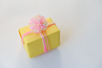 yellow gift box on a white background. winter holidays, pompom from threads, warm. unusual