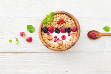 granola with berries on white wooden background