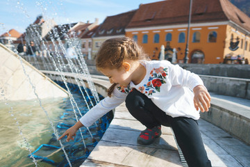 Fototapeta na wymiar girl playing with spray of fountain