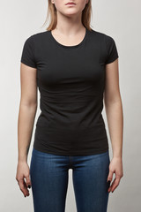 Obraz premium partial view of young woman in casual black t-shirt with copy space isolated on white