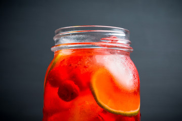 Red cocktail with cherry and lime in jar on the rustic background. Selective focus. Shallow depth of field.