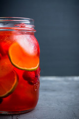 Red cocktail with cherry and lime in jar on the rustic background. Selective focus. Shallow depth of field.