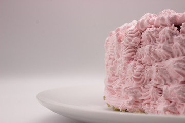 Obraz na płótnie Canvas The piece of a cream pink cake on a plate on a white-gray background. Image with a copy space area.