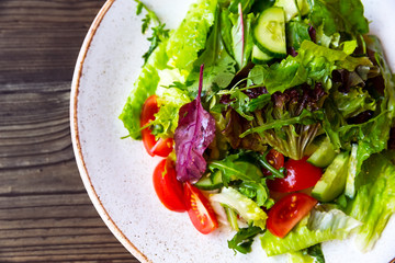Bowl of salad with vegetables on wooden table.