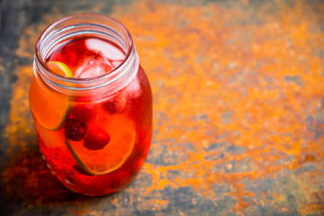 Red cocktail with cherry and lime in jar on the rustic background. Selective focus. Shallow depth of field.
