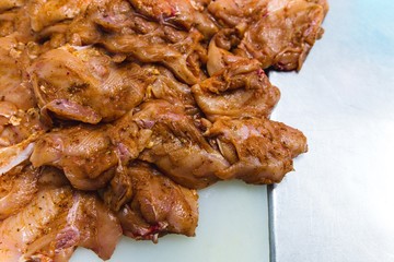 Chicken mixed with seasoning is prepared for cooking in a barbecue
