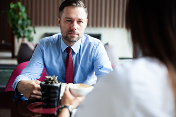 Flirting in a cafe. Beautiful loving couple sitting in a cafe enjoying in coffee and conversation. Love and romance