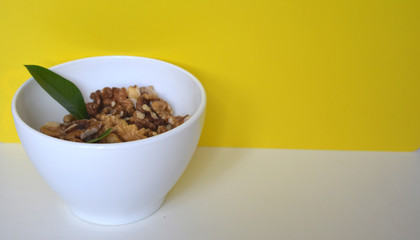 Nuts in a white saucer on a yellow background.