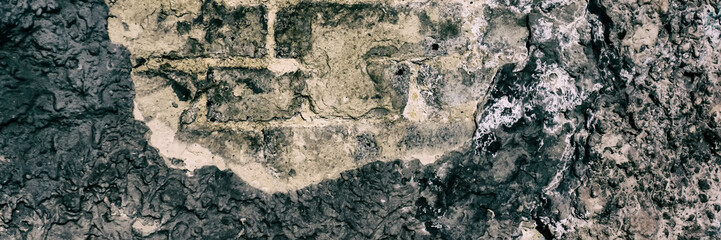 Brick wall surface covered with old crumbling cement plaster.