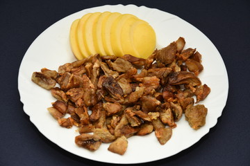 mushrooms fried with goldene apples sliced on a white plate