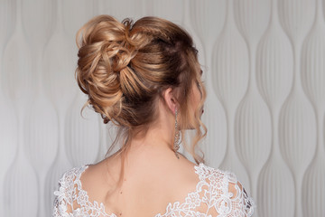 Wedding female hairstyle on the head of the girl blonde back view close-up on a light background. - 245930625