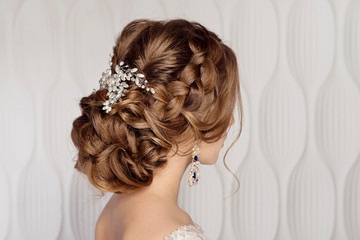 Wedding female hairstyle low beam on the head of a brown-haired girl back view on a light background. - 245930868