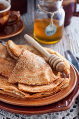 Homemade Russian openwork pancakes for carnival in honey, selective focus