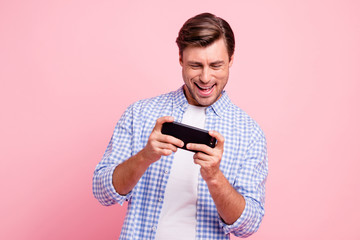 Close up photo of beautiful amazing brunet he him his handsome hold new telephone testing it win victory in video game wearing casual checkered plaid shirt outfit isolated on rose background
