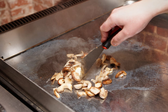 Chef is frying mushrooms on tepan pan