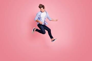 Full length body size photo of jumping high crazy he his him macho playing imagine electric guitar in arms hands hair fly wearing casual jeans checkered plaid shirt isolated on rose background