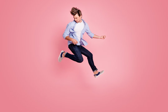 Full length body size photo of jumping high crazy he his him macho playing imagine electric guitar in arms hands hair fly wearing casual jeans checkered plaid shirt isolated on rose background