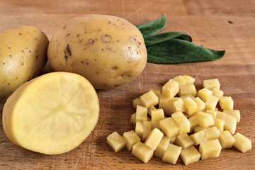 patate tagliate a cubetti e salvia su tagliere di legno