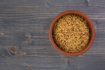 bowl of raw bulgur and quinoa on wooden table background