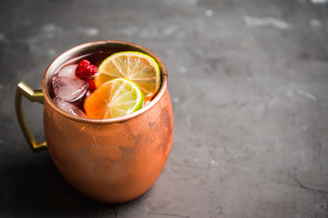 Sweet moscow mule with lime and raspberry in copper mug on the rustic background. Selective focus. Shallow depth of field. 