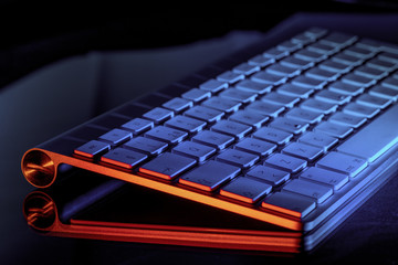 Aluminum computer keyboard illuminated in blue and red
