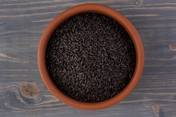 bowl of black wild rice on wooden table background, top view