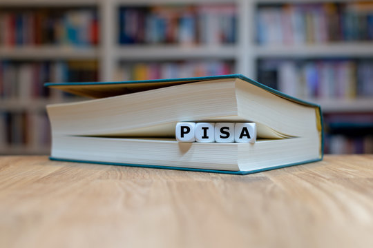 Würfel in einem Buch bilden das Wort "PISA" und symbolisieren die "PISA Studie"