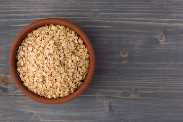 Rolled oats or oat flakes in bowl on wooden background. Healthy lifestyle, healthy eating concept. Top view