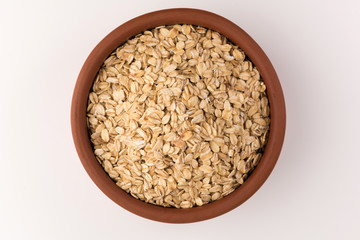 Dry rolled oatmeal in bowl isolated on white background. Top view