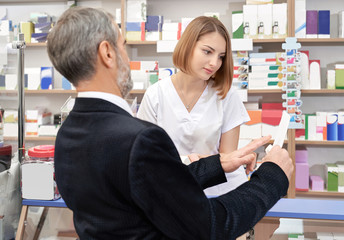 Customer showing to pharmacist prescription in drugstore.