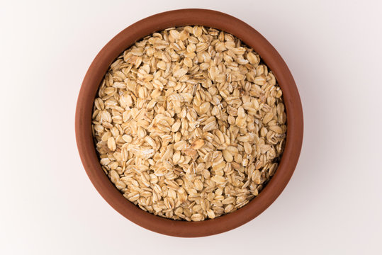 Dry Rolled Oatmeal In Bowl Isolated On White Background. Top View