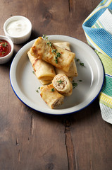 Savory crepe rolls with ground meat filling served with sour cream and tomato sauce