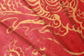 hand painted gold patterns and writing on a red fabric umbrella 