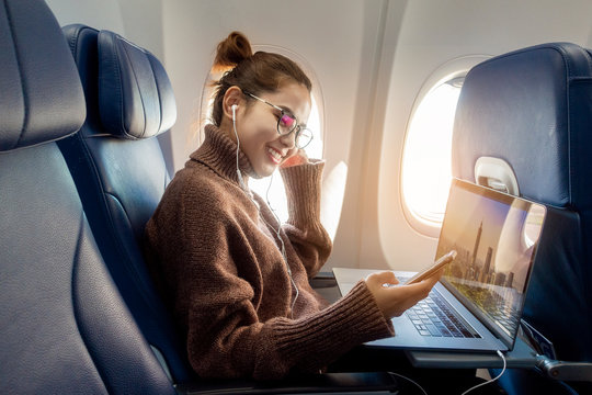 Beautiful Asian woman is working with laptop in airplane