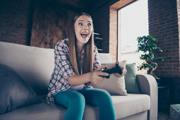 Low angle view photo portrait of cheerful ecstatic excited enthusiastic she her hipster teen girl using holding controller in hands playing wireless computer videogames © deagreez