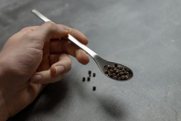 Pfefferkörner auf Löffel in Hand