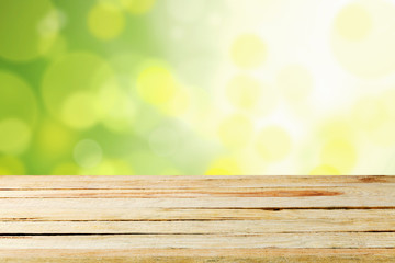 Fototapeta premium Empty wooden deck table with foliage bokeh.