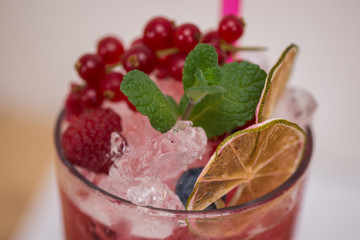 Tasty cold fresh drink lemonade with raspberry, mint, ice and lime in glass 