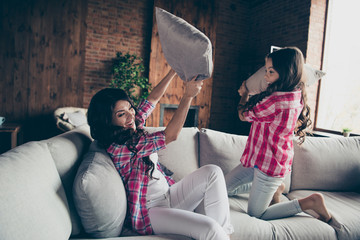 Portrait of nice-looking gorgeous cute lovely sweet attractive charming cheerful cheery wavy-haired people fighting pillows on divan vacation in house indoors