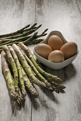 asparagi crudi sopra tavolo rustico con uova
