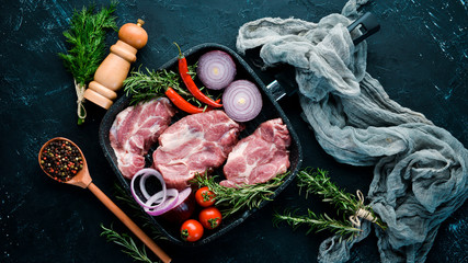 Raw steak. Meat with spices and herbs. On a black stone background. Top view. Free copy space.