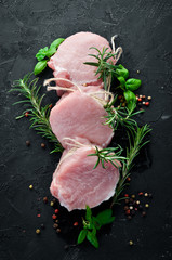 Raw meat, medallions with rosemary and spices. On a black stone background. Top view. Free copy space.