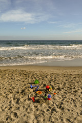 View of a sandy beach with coloured beach toys next to the water's edge, Laigueglia, Liguria, Italy