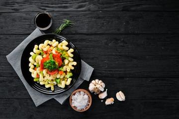 Pasta with vegetables. On a black background. Top view. Free space for your text.