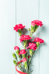 Bouquet of pink carnation on light turquoise wooden background. Top view with copy space.