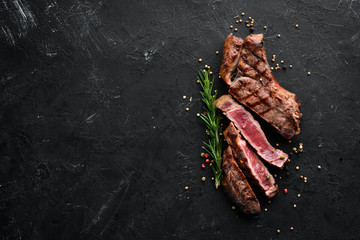 Veal steak on a bone on a black background. Free space for your text. Top view.