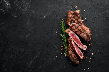 Fototapete Rund Veal steak on a bone on a black background. Free space for your text. Top view. © Yaruniv-Studio