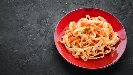 Pasta with vegetables and tomato sauce in a plate. On the old background. Top view. Free space for your text.