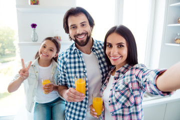 Self-portrait of nice cute sweet lovely attractive trendy cheerful positive people mom dad useful healthy fresh citrus squeezed juice c-vitamin showing v-sign in light white modern interior indoors